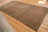 Distressed Malayer rug corner, intricate boteh patterns in dusty rust, sky blue, and ivory.