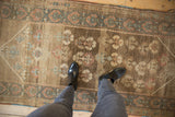 Distressed brown Serab runner with abrashed field, featuring blue, rust, and ivory plant motifs.