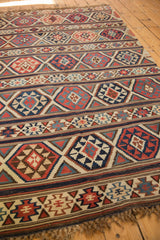 Antique Shirvan Kilim carpet detail: geometric bands, diamond motifs, navy, brick red, and beige.