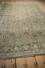 Distressed vintage Shiraz, close-up of faded Herati motif, time-softened green, ivory, brown tones.