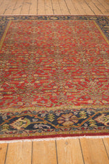 Vintage Mahal carpet showing rich brick red Herati field, navy blue vine border, and ivory fringe.