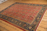Vintage Mahal rug corner with navy floral vine border and red Herati pattern.