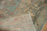 Folded corner of a distressed Yazd carpet, showing dusty floral patterns, wear, and woven foundation.