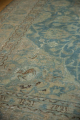 Close-up of distressed Tabriz rug showing faded sky blue, ivory vinery and animal motif.