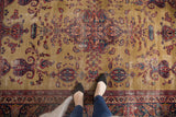 Vintage Sarouk rug featuring central medallion, germinating paisley, gold field, cartouches, and wear.