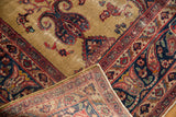 Folded Vintage Sarouk carpet corner, showing hand-knotted foundation and worn gold field with navy paisley.