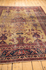 Vintage Sarouk carpet's gold field, germinating paisley, inscription cartouche, and navy border.