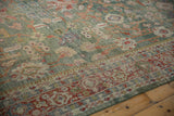 Distressed pile texture showing celadon green field and brick red floral border.