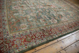 Distressed Mahal carpet corner, showing secured dark green edge and rich brick red floral border.