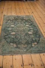 Distressed perimeter of the vintage Kashan rug, with floral elements and faded teal tones.