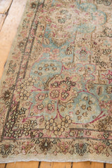 Distressed Kerman runner corner, showing faded sky blue, blush floral details and worn pile.