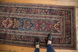 Top-down view of an antique Kerman runner, showcasing contrasting navy, red, and ivory floral patterns.