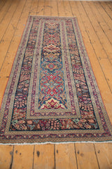 Intricate curvilinear palmettes in cochineal red, navy blue, and ivory tones on this antique Kerman runner.