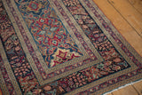 Intricate navy, red, bronze, and ivory curvilinear patterns on an antique Kerman rug.