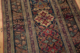 Intricate curvilinear medallions and dense floral vine patterns on this antique Kerman rug.