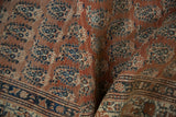 Detail of antique Tabriz runner showing repeating boteh with germinating plants and worn rust, navy tones.