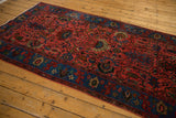 Raspberry red field with oversized palmettes, indigo border, and low pile texture.