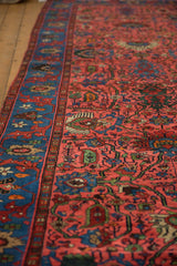 Traditional Persian Bijar runner's raspberry red field with allover palmettes and indigo blue border, showing low pile.