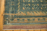 Distressed vintage Belouch rug corner with faded blue and sand guls, purple plain weave, and fringe.