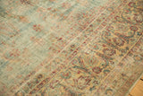 Distressed Kerman carpet featuring an elongated vinery border in red and ivory tones.