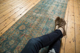 Distressed Mahal runner, ocean blue-green and terra cotta floral patterns, with person's feet.
