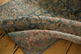 Worn pile of vintage distressed Meshed rug runner with ocean green, blush, and wine red scrolling patterns.