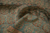 Distressed texture of vintage Malayer rug fold, showing faded raspberry and dusty blue patterns.