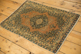 Angled view of an antique Persian Tabriz rug mat with scalloped medallion, floral detail in dusty terra cotta, navy, ivory.