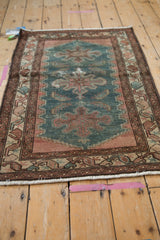 Hand-knotted distressed Hamadan rug corner with ivory fringe and patterned border.