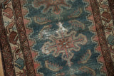 Textured indigo field with foundation wear, geometric motifs, and aubergine border.
