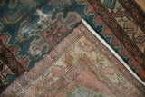 Folded vintage Distressed Hamadan rug, revealing worn indigo pile, exposed foundation, and fringe.