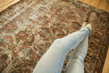 Distressed Baktiari rug texture with faded wine red and slate blue motifs under crossed legs.
