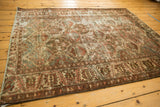 Distressed Baktiari rug border with wine red palmettes, ivory ground, and soft patina.