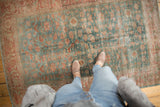 Distressed vintage Malayer rug with faded blue and blush palmette motifs, foundation visible.