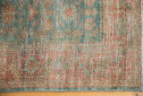 Distressed Persian Malayer rug detail, blush red and sky blue floral motifs, visible wear.