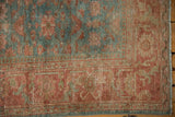 Vintage Malayer rug corner with blush red border, sky blue motifs, and textured wear.
