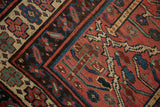 Vintage Kurdish carpet corner shows geometric plant motifs in madder red, navy, sky blue, and soft green.