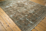 Angled view of vintage Kerman carpet with distressed texture, showcasing soft ocean green, brown vinery.
