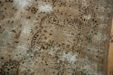 Distressed vintage Kerman carpet showing worn pile, subtle floral patterns, and muted earthy tones.