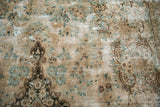 Worn texture of the distressed Kerman carpet revealing ocean green blue and brown vinery.