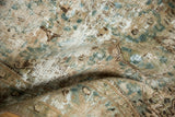 Distressed vintage Kerman carpet, close-up showing worn foundation and scrolling floral details in ocean green, beige.