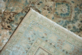 Distressed Kerman carpet corner revealing softened ocean green blue, sand pile and woven foundation.