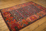 Antique Bijar rug corner: brick red garden border, navy Herati field, showing knot wear.