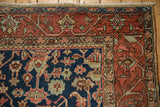 Heriz carpet corner with intricate madder root red border, navy field, and secured fringe.
