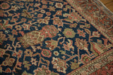 Intricate madder red, navy, and blush floral patterns on vintage Heriz rug border.