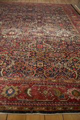 Aged vintage Mahal rug border, cherry red stylized florals, navy trefoil lattice pattern.