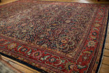 Vintage Mahal carpet edge with cherry red border and navy trefoil lattice pattern.