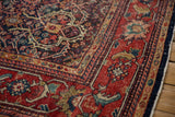 Vintage Mahal rug corner showing cherry red border, navy field with trefoil lattice, and low pile wear.