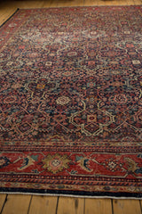 Angled view of the vintage Mahal carpet's worn navy and red trefoil lattice.