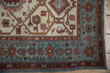 The even, hand-knotted pile and geometric border of a distressed vintage Hamadan rug corner.